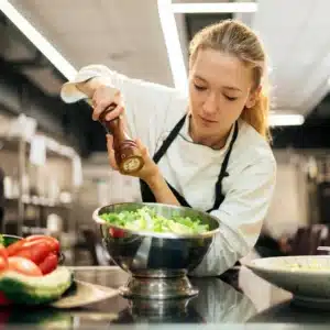 About Isabella Martinez seasoning a fresh green salad in the kitchen