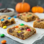 Close-up slice of chewy M&M’s Halloween Cookie Bar with melted chocolate chips