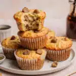 A close-up of high protein pancake sausage mini muffins on a plate, with one broken open to show the sausage and cheese.