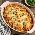 A ceramic casserole dish of buffalo chicken pasta bake fresh from the oven with browned cheese.