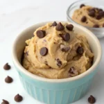 A small ceramic bowl filled with creamy high protein edible cookie dough topped with chocolate chips.