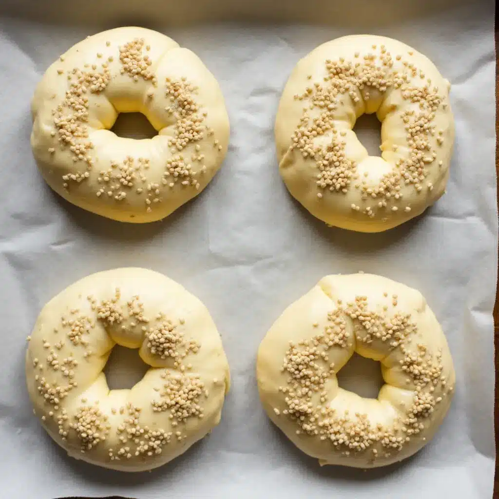 Raw bagel dough shaped into rounds on a parchment lined baking sheet, ready for the oven.