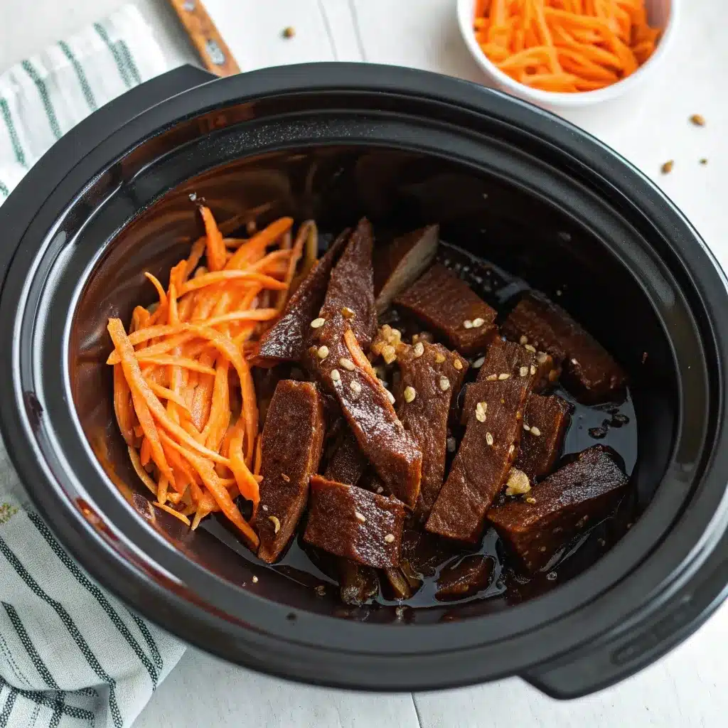 Raw coated beef and sauce ingredients in a slow cooker pot.