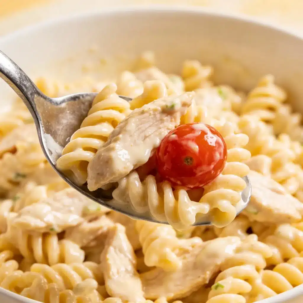 A serving spoon full of creamy chicken pasta salad.
