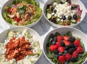 A collection of four different high protein salads in white bowls on marble.