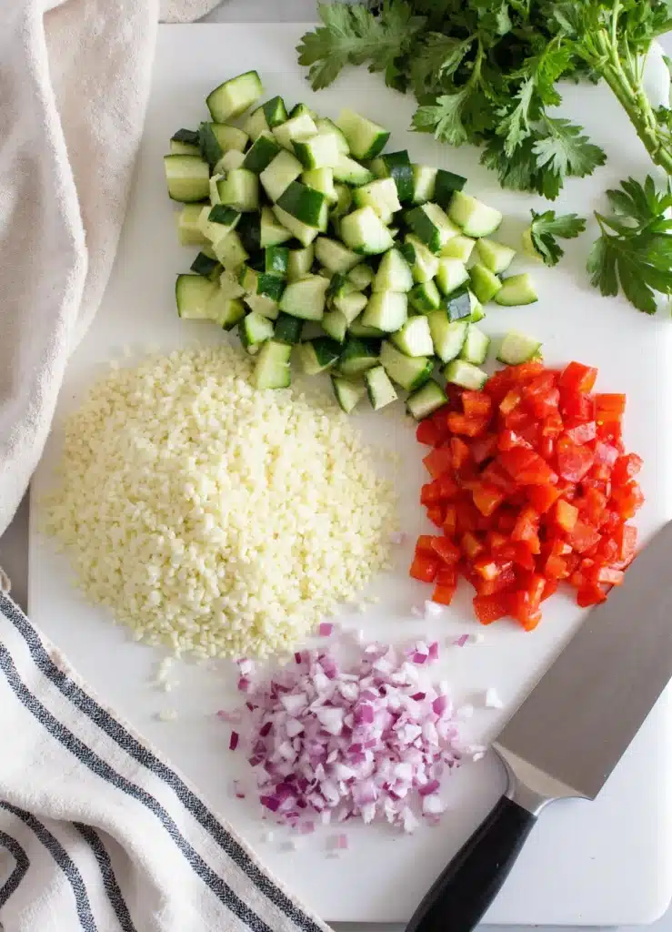 Finely diced cucumbers and onions on a cutting board.