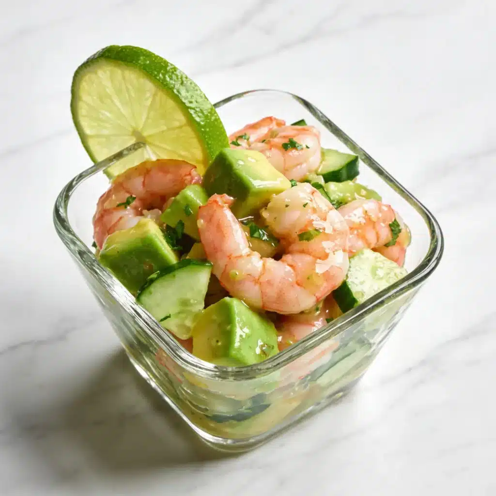 An elegant serving of healthy shrimp ceviche salad in a glass bowl with a lime garnish.