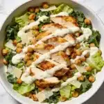 High protein chicken caesar salad with roasted chickpeas in a white bowl.