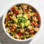A vibrant Cowboy Caviar Salad in a white bowl with chicken, black beans, and avocado.