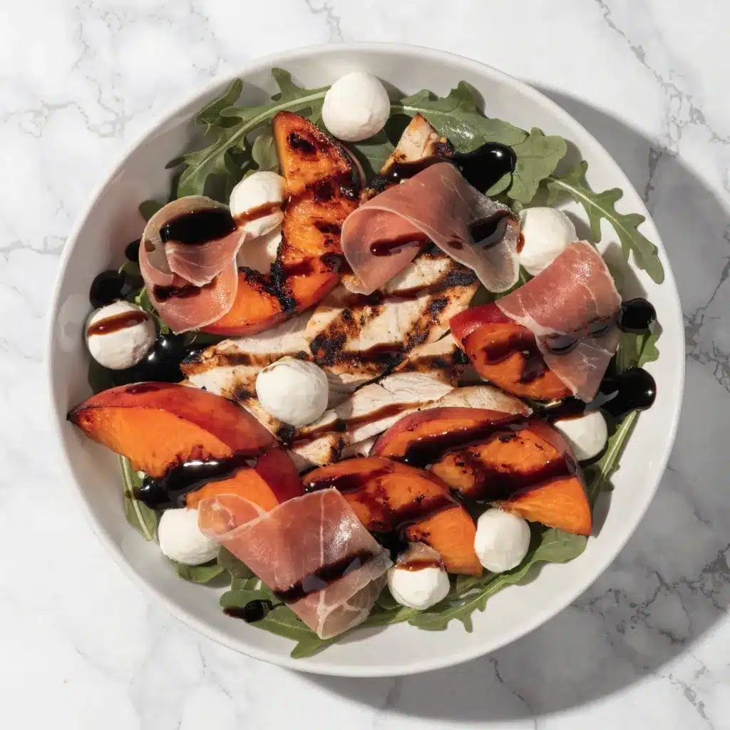 A vibrant Peach and Prosciutto Salad with grilled peaches and chicken on a white plate.