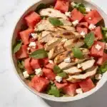 A finished bowl of Watermelon Feta Salad with Chicken featuring mint and balsamic glaze.