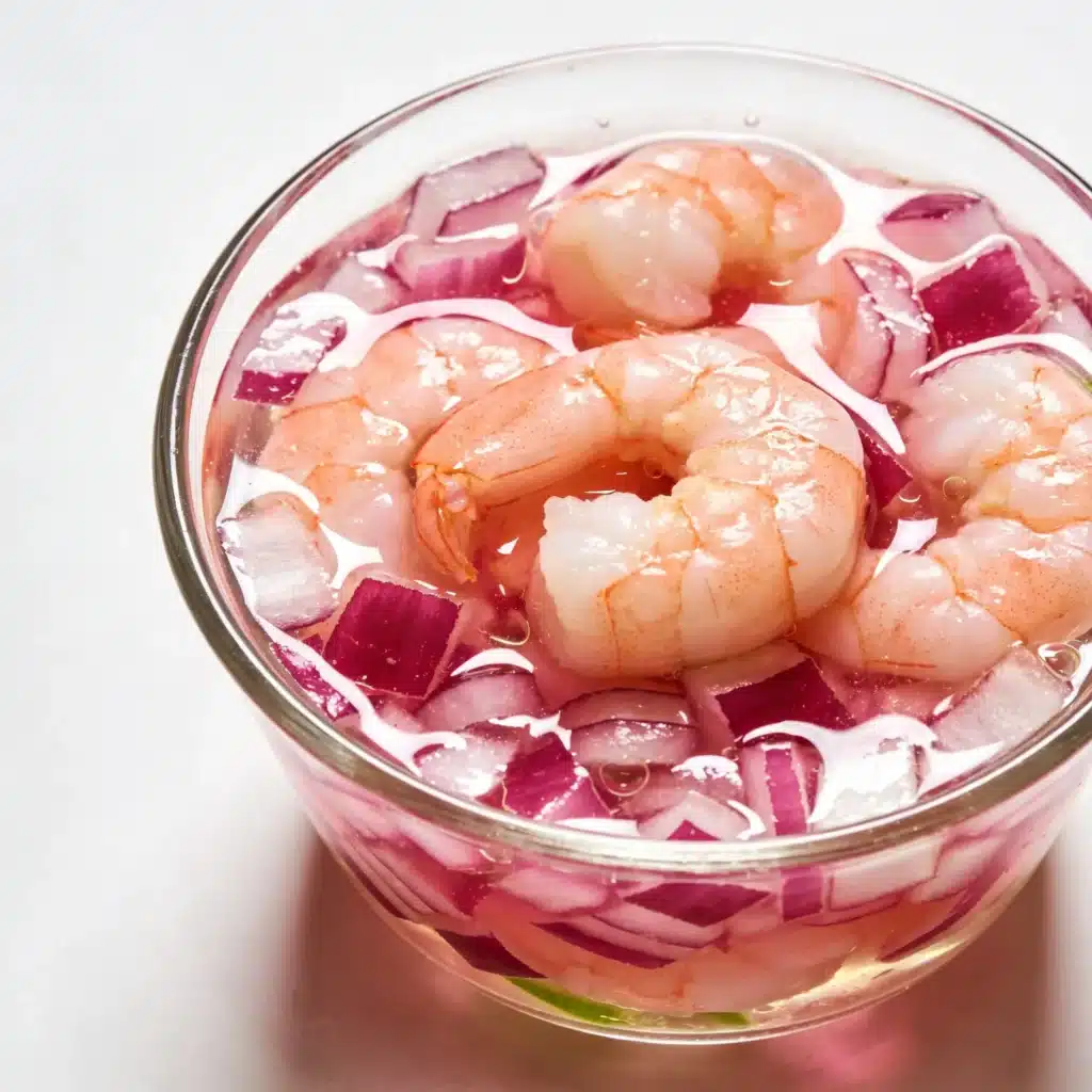 Shrimp and red onions marinating in fresh lime juice for a ceviche-style salad.