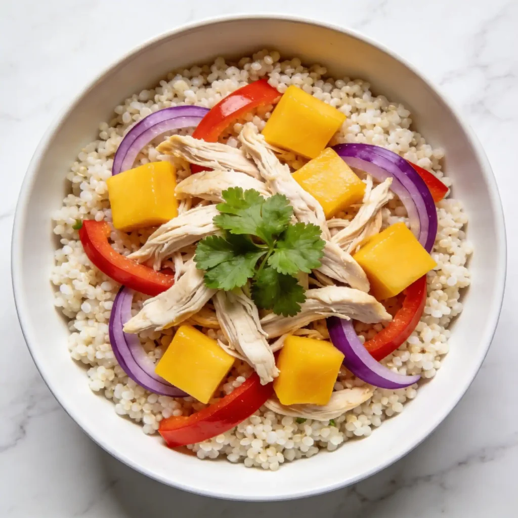 Mango chicken salad served as a power bowl over a bed of quinoa.