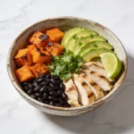 A professional high-angle view of a healthy black bean power bowl on a sunlit table.