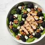A vibrant Blackberry and Goat Cheese Salad with grilled chicken and fresh spinach.