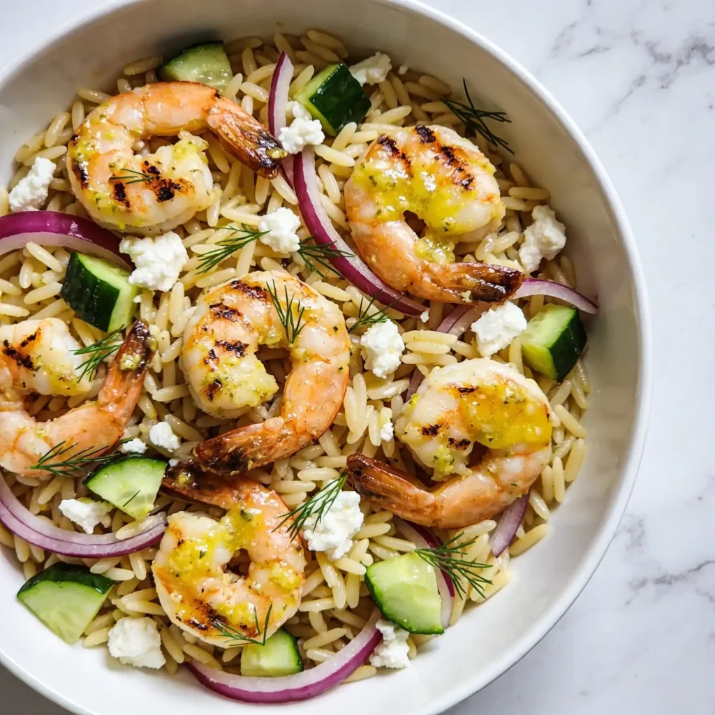 A Mediterranean orzo salad topped with lemon garlic grilled shrimp.