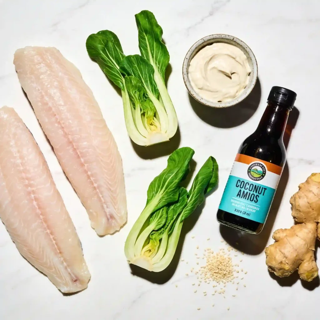 Fresh, raw ingredients for making baked cod and bok choy including white miso paste and fresh ginger.