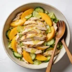 A large serving bowl of mango chicken salad, answering the question does ginger pair well with mango.