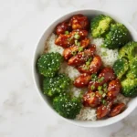 A top-down view of a high protein firecracker ground chicken bowl with broccoli and jasmine rice.