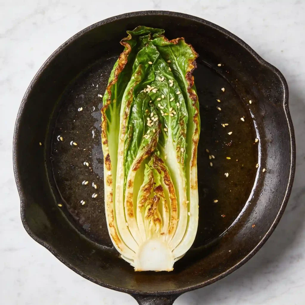 Halved baby bok choy beautifully seared in a cast iron skillet showing exactly how to cook baby bok choy.