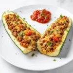 A close-up top-down view showing the seasoned ground turkey and melted cheese inside a zucchini boat.