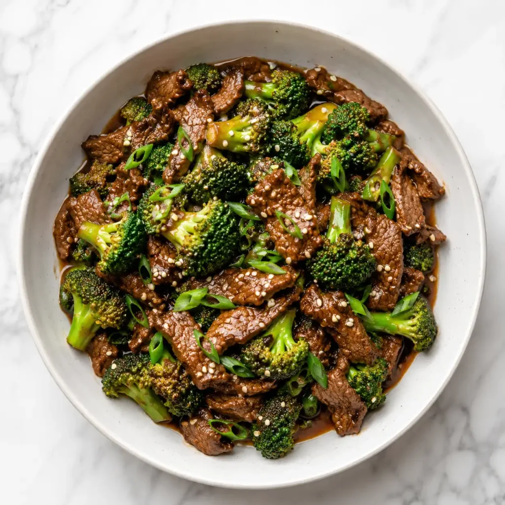 A close-up top-down view showing the glistening, tender texture of seared beef and crisp broccoli in a savory sauce.